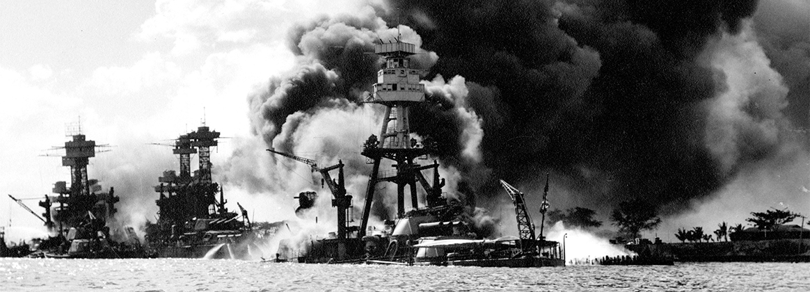 A historical photo of Battleship Row after the Japanese attack on Pearl Harbor, December 7, 1941.